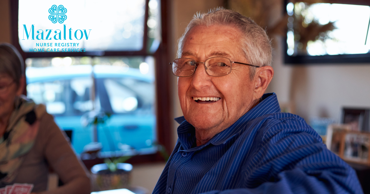 A smiling senior man is happily sitting at a table, enjoying aging in place as a result of successful of long-distance caregiving.
